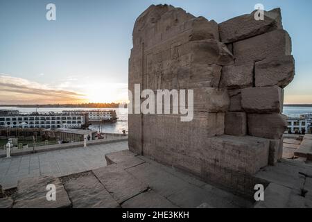 Eine alte Ruine am Kom Ombo Tempel mit Blick auf den Nil und angedockten Kreuzfahrtbooten, die Touristen zum historischen Denkmal bringen. Stockfoto