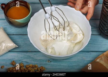 Eiweiß und Granulatzucker mit einem elektrischen Mixer schlagen. Stockfoto