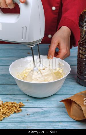 Eiweiß und Granulatzucker mit einem elektrischen Mixer schlagen. Stockfoto