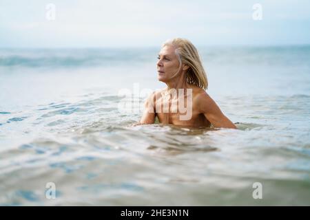 Elderige Frau in gutem Zustand, die im Meer baden. Stockfoto