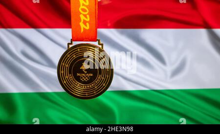 5. Januar 2021, Peking China. Goldmedaille der XXIV. Olympischen Winterspiele vor dem Hintergrund der ungarischen Flagge. Stockfoto