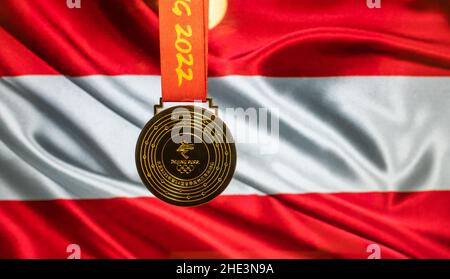 5. Januar 2021, Peking China. Goldmedaille der XXIV. Olympischen Winterspiele vor dem Hintergrund der österreichischen Flagge. Stockfoto