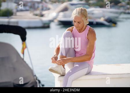 Ältere Frauen binden Schnürsenkel und machen sich bereit für die Fitness. Stockfoto