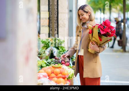 Frau, die die Früchte wählt, die sie in einem Gemüsehändler kaufen wird. Stockfoto