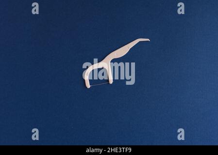 Weißer interdentaler Bogen, um Nahrung von den Zähnen zu entfernen. Zahngesundheit Blauer Hintergrund. Stockfoto