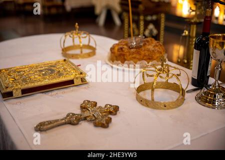 Kirkenkrone, Brot und ein goldenes Buch warten auf die Hochzeit des Brautpaten. Schöne Kirche in Bulgarien. Hochwertige Fotos Stockfoto