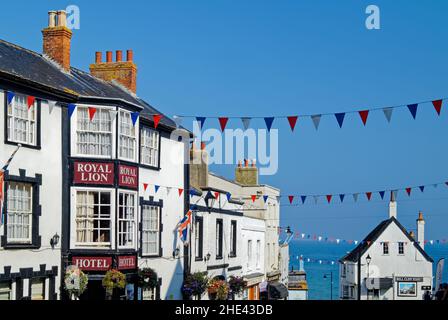 Großbritannien, Dorset, Lyme Regis, Broad Street Building und Bunting, einschließlich der Royal Lion und Bell Cliff. Stockfoto