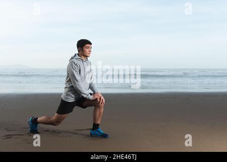 Hispanischer Teenager, der sich am Strand ausdehnt, während er sich auf seine Ziele konzentriert Stockfoto