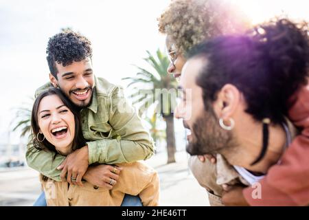 Junge Erwachsene Freunde mit Spaß Huckepack im Freien Stockfoto