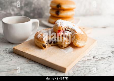 Frische und leckere gebissene Donuts mit verschiedenen Füllungen auf einem Holzbrett Stockfoto