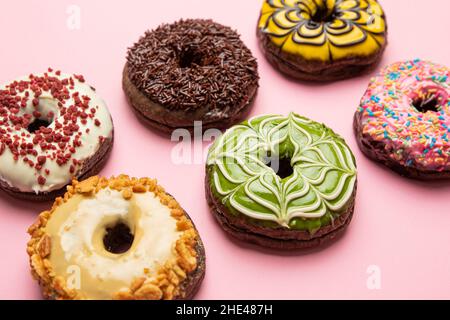 Eine Aufnahme frischer und köstlicher Donuts aus einem hohen Winkel auf einem rosafarbenen Tisch Stockfoto