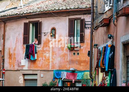 ROM, ITALIEN - 29. MÄRZ 2014: Eine alte Frau am Fenster in der gemütlichen alten Straße in Trastevere in Rom, Italien. Trastevere ist rione von Rom, an West-Verbot Stockfoto