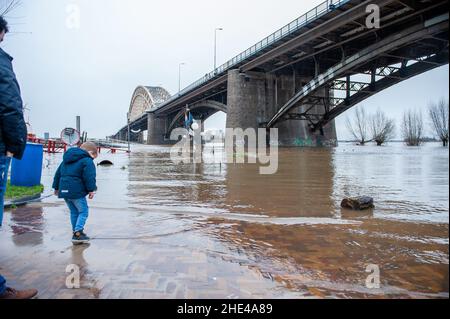 Nijmegen, Niederlande. 08th Januar 2022. In der Nähe der Waal-Brücke sieht man einen kleinen Jungen, der mit seinen Schuhen Wasser spritzt.das Wasser in den Flüssen steigt steil an. Morgens wurde sowohl in der Maas als auch am Rhein mit Hochwasser gerechnet. Selbst wenn der Wasserstand nicht so hoch war wie im letzten Januar, versammelten sich die Menschen um die Waalkaden, um den hohen Wasserstand zu sehen. Dieses Mal erreichte er an diesem Wochenende rund 13 Meter über NAP. NAP ist die Basis, die verwendet wird, um zu messen, wie hoch oder niedrig der Wasserstand ist. (Foto: Ana Fernandez/SOPA Images/Sipa USA) Quelle: SIPA USA/Alamy Live News Stockfoto