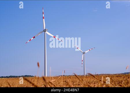 Zwei Windturbinen mit blauem Himmel im Hintergrund Stockfoto