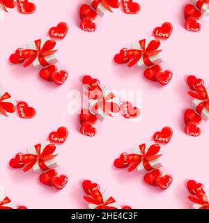 Geschenkbox mit leuchtend roten Schleife, Herzen und Liebe Worte wiederholen nahtlose Muster auf hellrosa Hintergrund. Valentinstag, Geburtstag, Muttertag sur Stockfoto