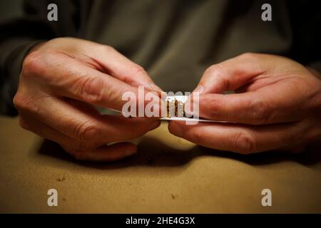 Ein Mann rollt ein Zigarettenpapier und füllt es mit losem Tabak Stockfoto