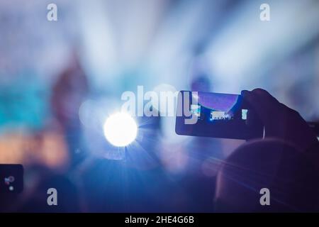 Verwenden Sie Advanced mobile Recording, Spaß Konzerte und schöne Beleuchtung, ehrliches Bild der Masse an Rock Konzert, Nahaufnahme von der Aufnahme von Video mit Smartphone Stockfoto