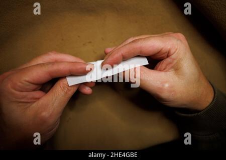 Ein Mann rollt ein Zigarettenpapier und füllt es mit losem Tabak Stockfoto