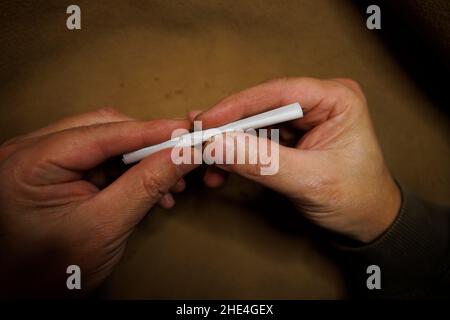 Ein Mann rollt ein Zigarettenpapier und füllt es mit losem Tabak Stockfoto