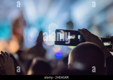 Verwenden Sie Advanced mobile Recording, Spaß Konzerte und schöne Beleuchtung, ehrliches Bild der Masse an Rock Konzert, Nahaufnahme von der Aufnahme von Video mit Smartphone Stockfoto