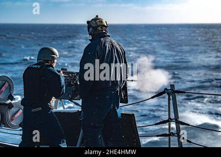 PAZIFISCHER OZEAN (Jan 5, 2022) Fire Controlman 2nd Klasse Leonardo Chandra, links, aus Monterey Park, Kalifornien, feuert unter der Aufsicht von Chief Gunner's Mate Christopher Lamotte, rechts, aus Moreno Valley, Kalifornien, ein Maschinengewehr vom Kaliber M2A1 .50 an Bord des Arleigh Burke-Klasse-Lenkrakenzerstörers USS Spruance (DDG 111). Spruance ist Teil der Abraham Lincoln Carrier Strike Group unter der Leitung der Carrier Strike Group 3, die am 3. Januar in San Diego zur Unterstützung globaler maritimer Sicherheitsoperationen eingesetzt wurde. Ein integraler Bestandteil der US-Pazifikflotte, US-3rd-Flotte operat Stockfoto