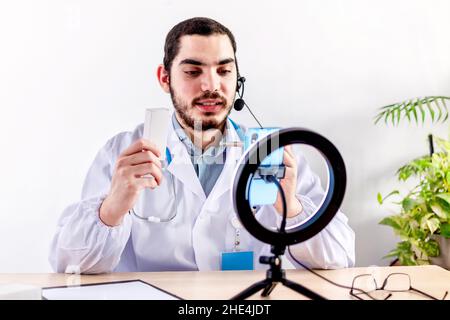 Positiver Arzt in Ohrhörern, der Online-Konsultation mit dem Patienten hat. Stockfoto