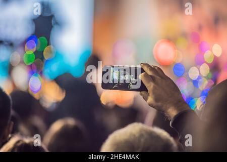 Verwenden Sie Advanced mobile Recording, Spaß Konzerte und schöne Beleuchtung, ehrliches Bild der Masse an Rock Konzert, Nahaufnahme von der Aufnahme von Video mit Smartphone Stockfoto