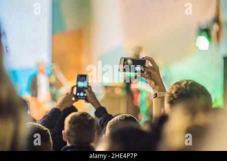 Verwenden Sie Advanced mobile Recording, Spaß Konzerte und schöne Beleuchtung, ehrliches Bild der Masse an Rock Konzert, Nahaufnahme von der Aufnahme von Video mit Smartphone Stockfoto