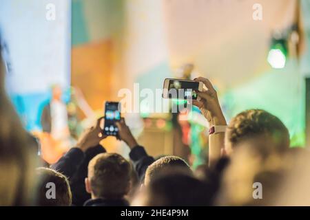 Verwenden Sie Advanced mobile Recording, Spaß Konzerte und schöne Beleuchtung, ehrliches Bild der Masse an Rock Konzert, Nahaufnahme von der Aufnahme von Video mit Smartphone Stockfoto