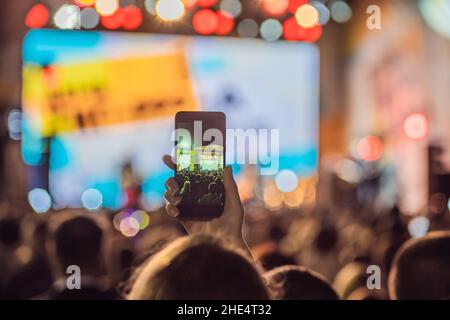 Verwenden Sie Advanced mobile Recording, Spaß Konzerte und schöne Beleuchtung, ehrliches Bild der Masse an Rock Konzert, Nahaufnahme von der Aufnahme von Video mit Smartphone Stockfoto