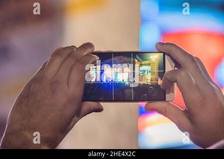 Verwenden Sie Advanced mobile Recording, Spaß Konzerte und schöne Beleuchtung, ehrliches Bild der Masse an Rock Konzert, Nahaufnahme von der Aufnahme von Video mit Smartphone Stockfoto