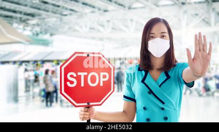 Asiatische Frau öffnen die Hand bei der Stop-Action und zeigen Banner Stop-Schild für foriener Reisende auf Flughafen-Station Stockfoto