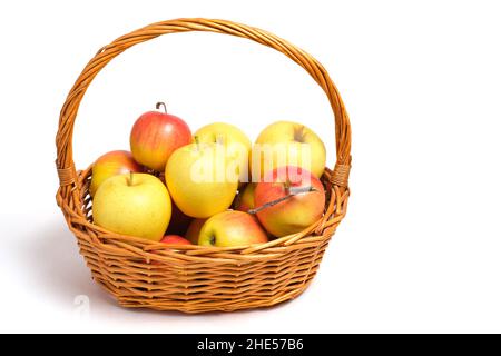 Früchte, Äpfel und Mandarinen in einem Weidenkorb auf weißem Hintergrund Stockfoto