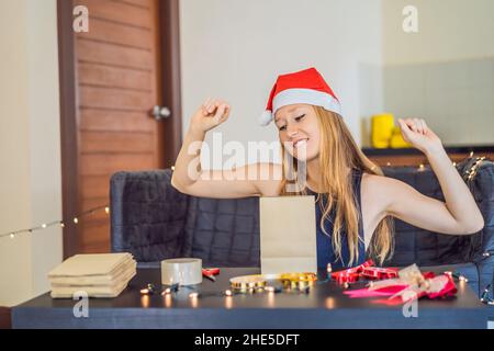 Junge Frau ist Verpackung präsentiert. Derzeitige eingewickelt in Handwerk Papier mit einer Rot und Gold Ribbon für Weihnachten oder Neujahr. Frau macht einen Adventskalender Stockfoto