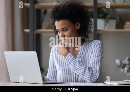 Nachdenkliche junge afrikanische Ethnizität Geschäftsfrau, die am Computer arbeitet. Stockfoto
