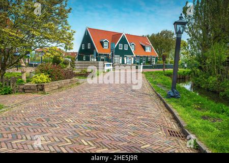 Schöner Blick auf die Straße mit gepflastertem Gehweg und engem Wasserkanal, Marken, Niederlande, Europa Stockfoto