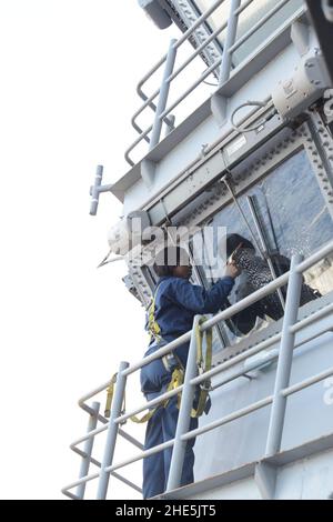 Der Seemann putzt die Fenster auf der Brücke auf dem Meer (8369876705). Stockfoto