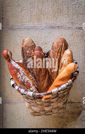 Laibe frisch gebackenes rustikales Brot in einem Korb, der in einer handwerklichen Bäckerei in Donostia oder San Sebastian, Spanien, ausgestellt wird Stockfoto