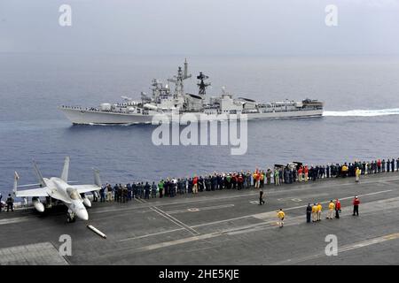 Seeleute an Bord des Flugzeugträgers USS Carl Vinson der Nimitz-Klasse begrüssen indische Marineschiffe. Stockfoto