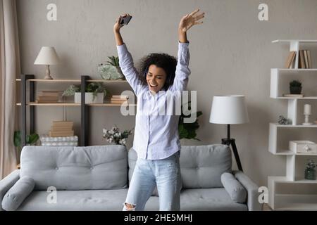 Entspannte junge afroamerikanische Frau, die mit Kopfhörern Musik hört. Stockfoto