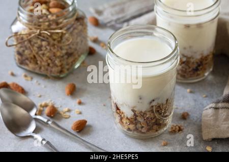 Gesundes Frühstück, Joghurt-Parfait. Joghurt mit hausgemachtem Mandelgranola auf grauem Betongrund. Stockfoto