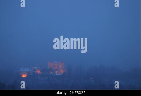 Schwangau, Deutschland. 09th Januar 2022. Im Morgennebel steht die beleuchtete Burg Hohenschwangau. Quelle: Karl-Josef Hildenbrand/dpa/Alamy Live News Stockfoto