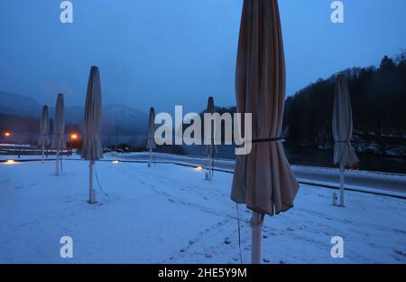 Schwangau, Deutschland. 09th Januar 2022. Die gefalteten Sonnenschirme eines Restaurants stehen vor dem Alpsee, der im Morgennebel liegt. Quelle: Karl-Josef Hildenbrand/dpa/Alamy Live News Stockfoto