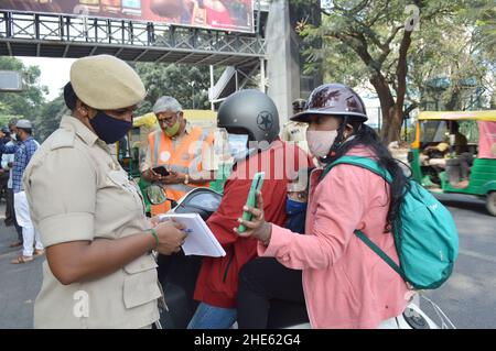 Bangalore, Indien. 8th Januar 2022. Ein Verkehrspolizist hält während der ersten Ausgangssperre am Wochenende ein Fahrzeug an einem Straßenkontrollpunkt an, um die Ausbreitung des COVID-19 in Bangalore, Indien, am 8. Januar 2022 einzudämmen. Quelle: Str/Xinhua/Alamy Live News Stockfoto