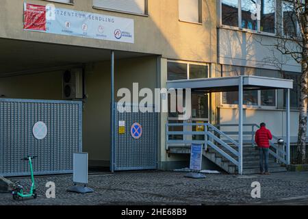 Ein Mann in einer roten Jacke wartet rauchend vor einem Corona Testcenter in München Sendling. Stockfoto