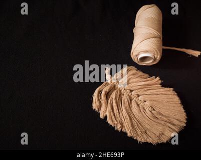 Schöne Macramé oder Macrame Handwerk und Rolle von Macrame Schnur in dunklem Hintergrund. Platz für Text. Nahaufnahme. Stockfoto