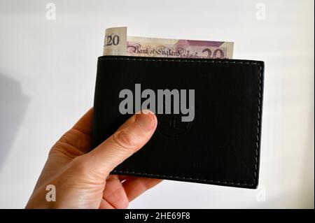 Nahaufnahme eines Mannes, der eine Brieftasche mit einem 20-Pfund-Schein hält. Stockfoto