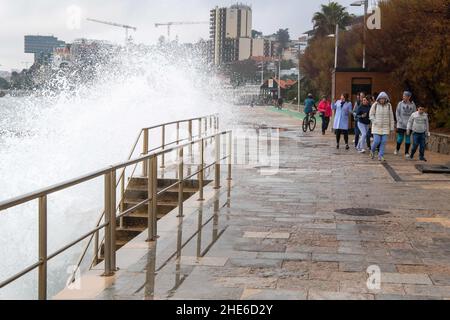 Cascais, Portugal. 03rd Januar 2022. Eine Welle stürzt auf einem Gehweg in der Nähe einiger Fußgänger an der Küste von Cascais ab. Portugal verzeichnete seit Beginn der Pandemie 1.577.784 Fälle und 19.071 Todesfälle im Zusammenhang mit Covid-19, so das Bulletin der Generaldirektion Gesundheit (DSG). (Foto von Jorge Castellanos/SOPA Images/Sipa USA) Quelle: SIPA USA/Alamy Live News Stockfoto