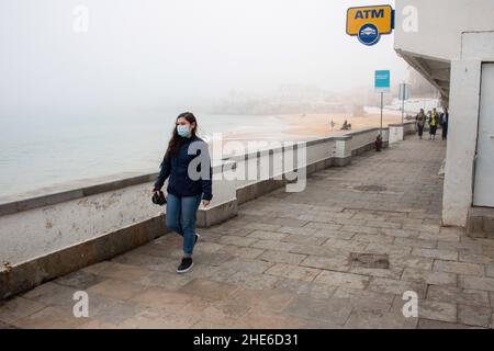 Cascais, Portugal. 03rd Januar 2022. Eine Frau mit Schutzmaske geht entlang der Küste in Cascais. Portugal verzeichnete seit Beginn der Pandemie 1.577.784 Fälle und 19.071 Todesfälle im Zusammenhang mit Covid-19, so das Bulletin der Generaldirektion Gesundheit (DSG). (Foto von Jorge Castellanos/SOPA Images/Sipa USA) Quelle: SIPA USA/Alamy Live News Stockfoto