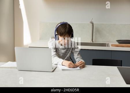 Fokussierter Teenager-Schuljunge mit Kopfhörern, der virtuelle Klasse besucht Stockfoto